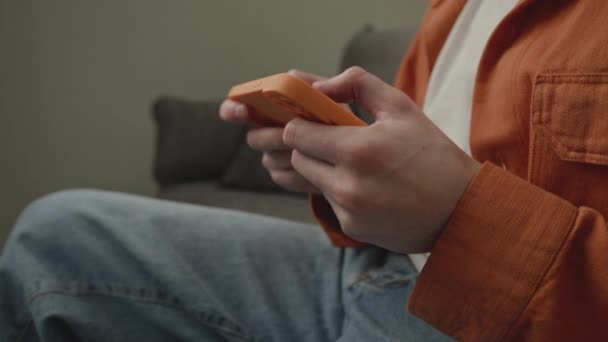 男人玩视频游戏使用手机关闭 有智能手机在沙发上的男人手持相机 — 图库视频影像