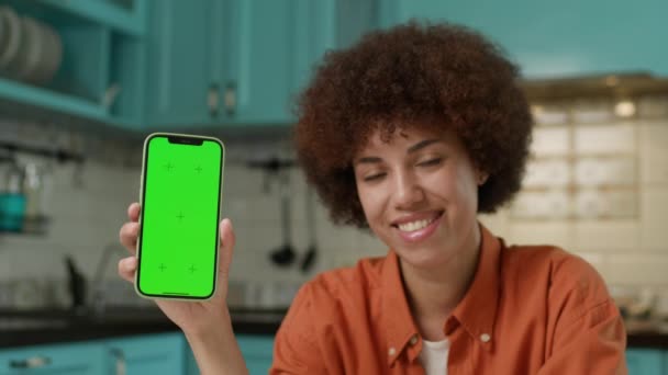 カメラで携帯電話のクロマキーを表示する陽気な女性 アフリカ系アメリカ人女性が携帯電話の緑色のスクリーンをカメラで見ている 4Kについて — ストック動画