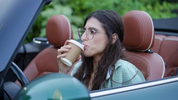 Γυναίκα Πίνοντας Καφέ Κάθεται Μετατρέψιμο Αυτοκίνητο Νεαρή Ενήλικη Οδηγός Χαμογελάει — Αρχείο Βίντεο