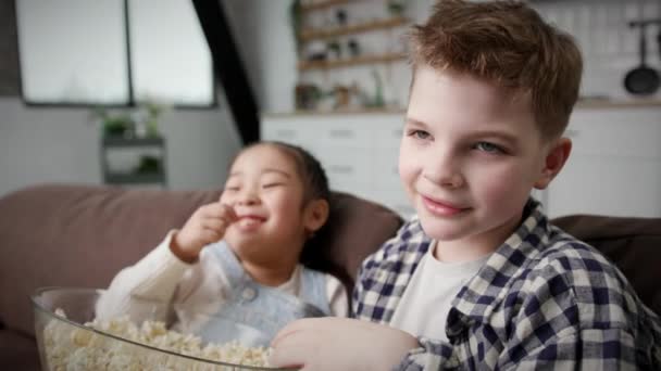Мультирасові Діти Їдять Попкорн Сидячи Софі Близько Дівчинка Хлопчик Сміються — стокове відео