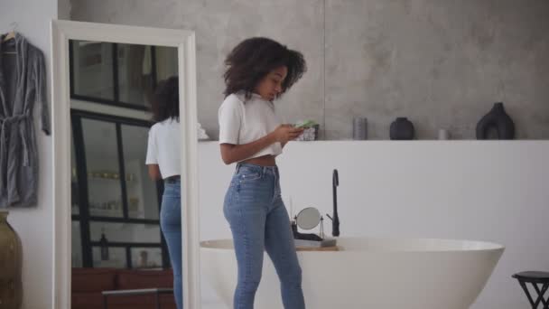 Femme Noire Faisant Défiler Son Téléphone Marchant Dans Salle Bain — Video