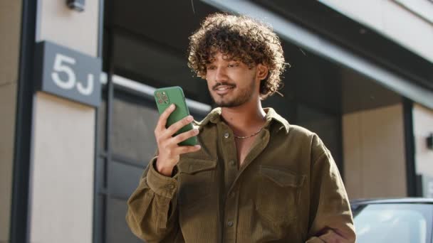 カメラでスマートフォングリーン画面を表示する20代男性 外に立っているクロマキーの携帯電話のスクリーンを握るインドの男 4Kについて — ストック動画