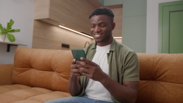 Hombre Negro Mensajes Texto Teléfono Celular Sentado Sofá Veinteañeros Hombre — Vídeos de Stock