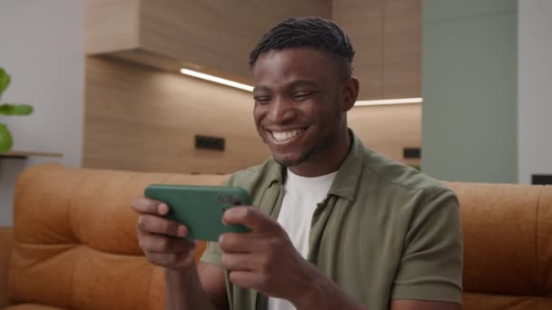黑衣人在家里用手机赢了电子游戏 快乐的非裔美国人手握智能手机玩手机游戏应用程序 — 图库视频影像