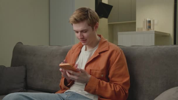 20代男性が携帯電話で悪いニュースを読んでいます 自宅でスマートフォンを使用している人を怒らせます 4Kについて — ストック動画