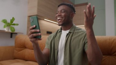Siyahi Adam, Akıllı Telefon 'u kullanarak görüntülü arama yapıyor. Evdeki koltukta oturan Afrikalı Amerikalı bir adam cep telefonuyla konuşuyor. 4K