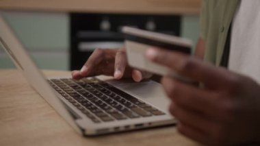Bilgisayarı ve banka kartını kullanarak online ödeme yapan siyah eller. Tanınmayan Afro-Amerikan erkek internet alışverişi yapıyor. Yakın çekim. 4K