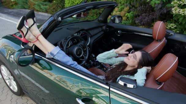妇女在可转换汽车中放松 女司机躺在车里对着镜头笑 — 图库视频影像