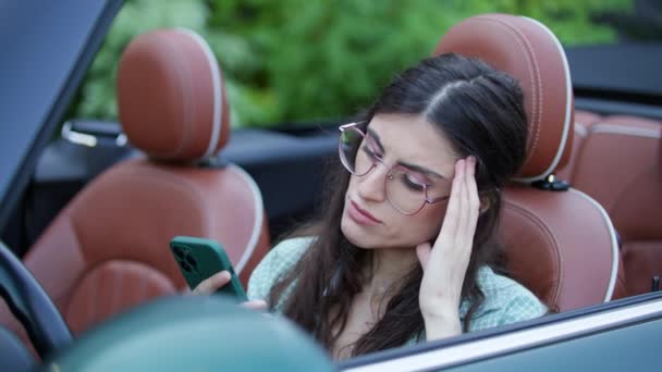 开车的女人坐在车里看坏消息 女司机在浏览手机时感到沮丧 她智能手机上的坏消息4K — 图库视频影像