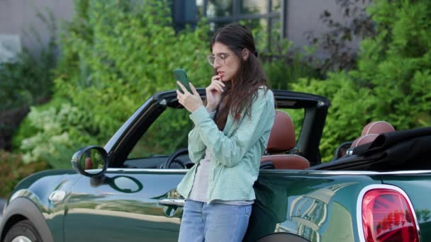 站在汽车旁边看坏消息的女人 女司机在浏览手机时感到沮丧 她智能手机上的坏消息4K — 图库视频影像