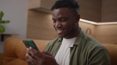 Siyah adam koltukta oturan cep telefonuyla mesajlaşıyor. 20 'li yaşlarda Afro-Amerikan bir erkek akıllı telefon bağımlısı. 4K