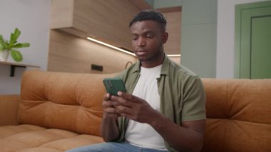 Siyah adam koltukta oturan cep telefonuyla mesajlaşıyor. 20 'li yaşlarda Afro-Amerikan bir erkek akıllı telefon bağımlısı. 4K