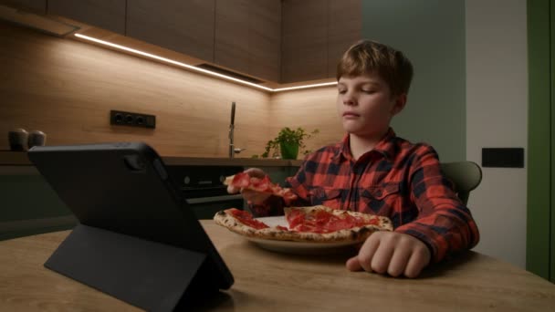 子供はタブレットのコンピュータに囲まれて おいしいピザのスライスを食べる テクノロジーと食事の楽しみの現代的なブレンドを描写するのに最適 — ストック動画