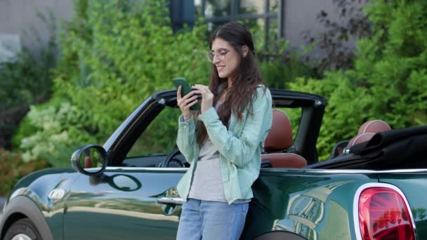 Frau Scrollt Smartphone Steht Draußen Neben Cabrio Junge Erwachsene Fahrer — Stockvideo