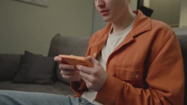 Video Oyunu Oynayan Adam Cep Telefonu Yakından Kullanıyor. Kanepede akıllı telefonu olan bir adam. El kamerasıyla. 4K