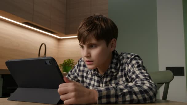 自閉症の少年はタブレットを通してオンライン学習を受け入れ 自宅の快適さから豊かなビデオレッスンに没頭します — ストック動画
