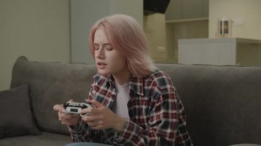 Çıkan Kadın Video Oyun Tutucu Joystick oynuyor. 20 'li yaşlarda, evdeki kanepede oturan video oyunu kazanan bir kadın. Maç zaferiyle mutlu. 4K