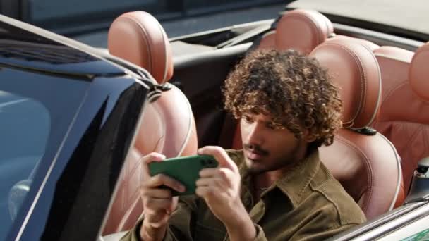車で座っている携帯電話のゲームをルーズする男 インドの男性ドライバーは 外に座っているスマートフォンを使用してゲームを失いました 4Kについて — ストック動画