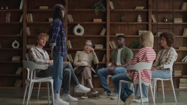 Ein Kreis Fokussierter Teilnehmer Diskutiert Während Einer Gruppentherapie Mit Holzbücherregalen — Stockvideo