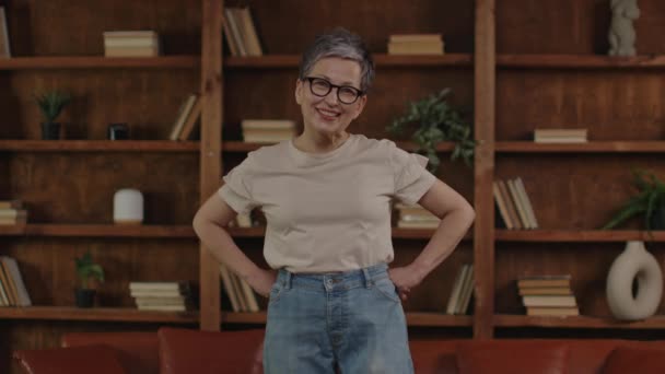 Glückliche Seniorin Mit Großen Jeans Nach Gewichtsverlust Einem Gemütlichen Raum — Stockvideo