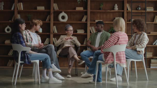 Group Diverse Individuals Engaging Conversation Cozy Room Bookshelves Plants — Stock Video