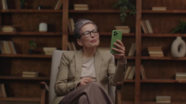 Starší Terapeut Brýlích Pomocí Smartphonu Pro Videohovor Knihovnou Pozadí — Stock video
