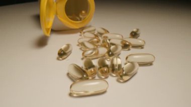 Açık bir konteynırdan dökülen çeşitli besin kapsüllerinin dinamik bir görüntüsü.