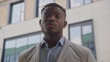 Kendine güveni tam genç bir adam şık günlük giysiler içinde dışarıda duruyor.