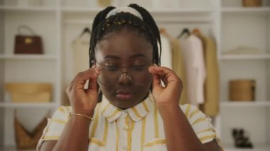 Genç bir kadın butikte gözlüğünü çıkarıyor.