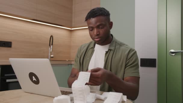 Young Man Examining Receipts Laptop Kitchen Counter — Stock Video