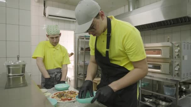 两个穿着黄色衣服的人精心装饰着披萨 — 图库视频影像
