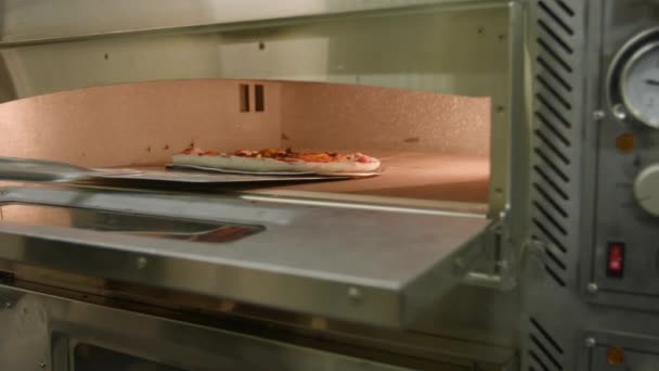 新鮮にトッピングされたピザがプロのキッチンオーブンの高熱にグライド ストック映像