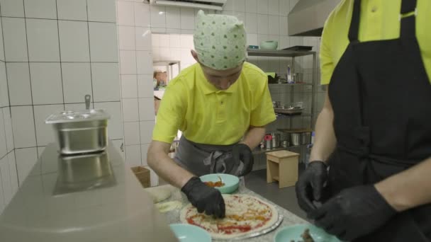 Två Personer Gul Klädsel Minutiöst Garnera Pizza — Stockvideo