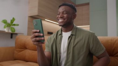 Siyahi Adam, Akıllı Telefon 'u kullanarak görüntülü arama yapıyor. Evdeki koltukta oturan Afrikalı Amerikalı bir adam cep telefonuyla konuşuyor. 4K