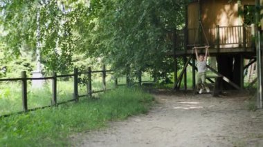 Güneşli bir parktaki bungee 'de sallanan bir çocuk, yaz oyununun heyecanını ve heyecanını yakalıyor.