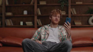 Sanal iletişimi kucaklayan bir adam cep telefonuyla bir video görüşmesi yapar. Evinin rahatlığından başkalarıyla bağlantı kurar.