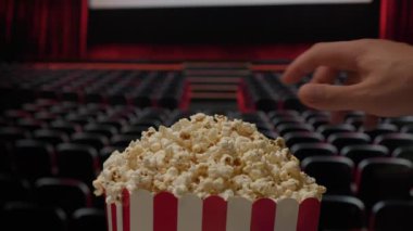 Bir el sinemada patlamış mısır sepetine uzanır ve film gösterimi sırasında klasik bir film atıştırma anını yakalar.