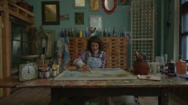 Ressam fırçayla şaheser yaratıyor. Kadın ressam atölyede oturuyor. Sanat atölyesinde çalışan bir kadın. 4K