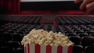 Bir el sinemada patlamış mısır sepetine uzanır ve film gösterimi sırasında klasik bir film atıştırma anını yakalar.