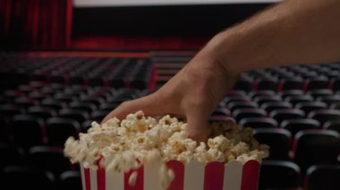 Bir el sinemada patlamış mısır sepetine uzanır ve film gösterimi sırasında klasik bir film atıştırma anını yakalar.