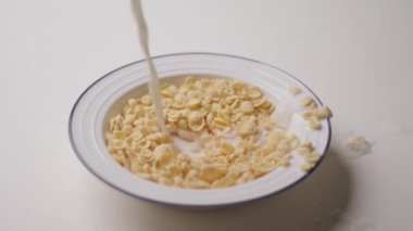 Bir kase gevrek mısır gevreğine dökülen sütün yakın plan görüntüsü lezzetli bir kahvaltı sahnesi oluşturuyor. Yemek için mükemmel, sabah rutini, ya da yaşam tarzı içeriği