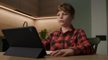 Bir çocuk evde bir tablet kullanarak, e-öğrenme ve eğitimdeki modern teknolojiyi gösteren çevrimiçi bir derse giriyor. Eğitim, teknoloji ve uzaktan öğrenme içeriği için mükemmel
