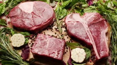 Köy ahşap bir masada sergilenen T-bone ve Osso Buco kesikleri de dahil olmak üzere farklı türde çiğ biftek. Aşçılık, yemek pişirme ya da kasaplık için mükemmel.