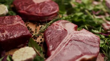 Köy ahşap bir masada sergilenen T-bone ve Osso Buco kesikleri de dahil olmak üzere farklı türde çiğ biftek. Aşçılık, yemek pişirme ya da kasaplık için mükemmel.