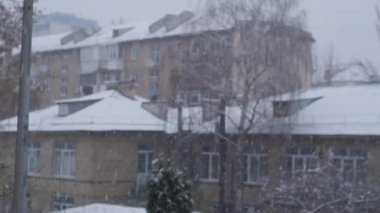 Şehir merkezine kar yağar, sokaklar, binalar ve ağaçlar örtülür. Şehirde kar yağışının güzelliğini yansıtan sakin ve resimli bir kış sahnesi.
