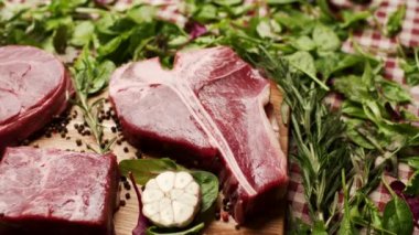 Köy ahşap bir masada sergilenen T-bone ve Osso Buco kesikleri de dahil olmak üzere farklı türde çiğ biftek. Aşçılık, yemek pişirme ya da kasaplık için mükemmel.