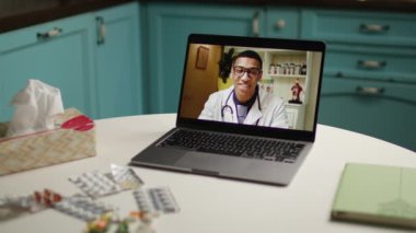 Çevrimiçi doktor konsültasyonunu gösteren bir dizüstü bilgisayar, çeşitli ilaç ve ilaçlarla çevrili bir masada duruyor. Teletıp, sağlık, online istişareler için ideal