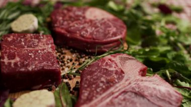 Köy ahşap bir masada sergilenen T-bone ve Osso Buco kesikleri de dahil olmak üzere farklı türde çiğ biftek. Aşçılık, yemek pişirme ya da kasaplık için mükemmel.