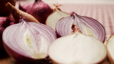 Tahta bir kesme tahtasına yerleştirilmiş kırmızı, sarı ve beyaz soğanlar da dahil olmak üzere çeşitli soğan parçalarının yakın çekimi. Mutfak, yemek ve sağlıklı besinler için mükemmel.