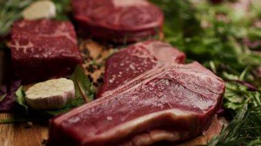 Köy ahşap bir masada sergilenen T-bone ve Osso Buco kesikleri de dahil olmak üzere farklı türde çiğ biftek. Aşçılık, yemek pişirme ya da kasaplık için mükemmel.